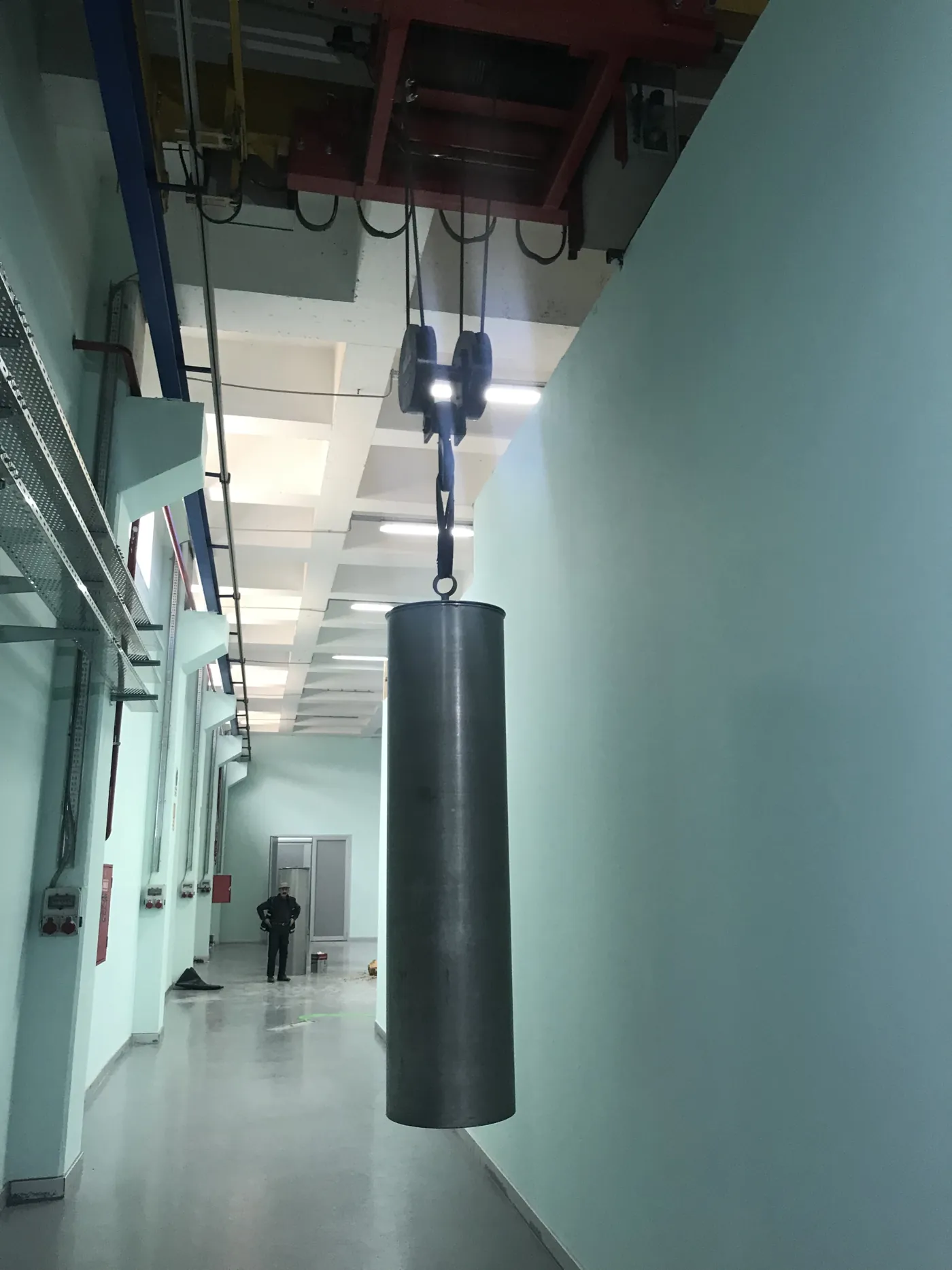 a cylindrical extractor basket hanging from a hoist in the production corridor